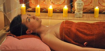 Liegende Frau bei einer Massage-Therapie mit Kerzen-Hintergrund